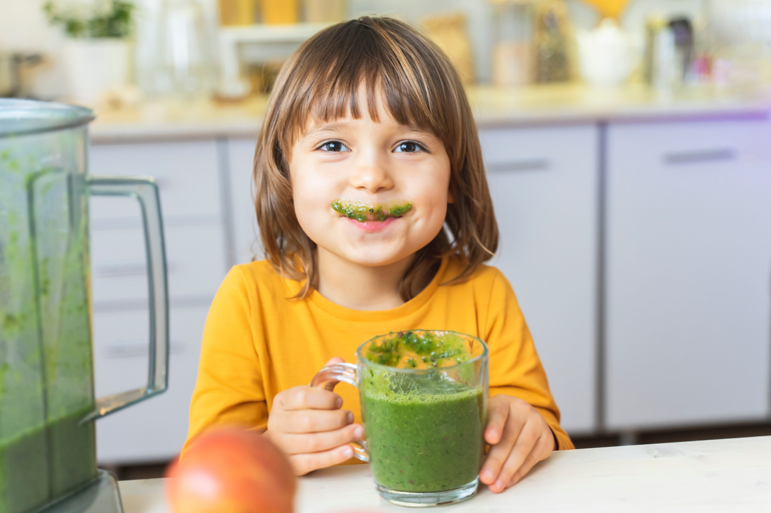 image of a Happy child with a mug of green smoothies in his hands. 